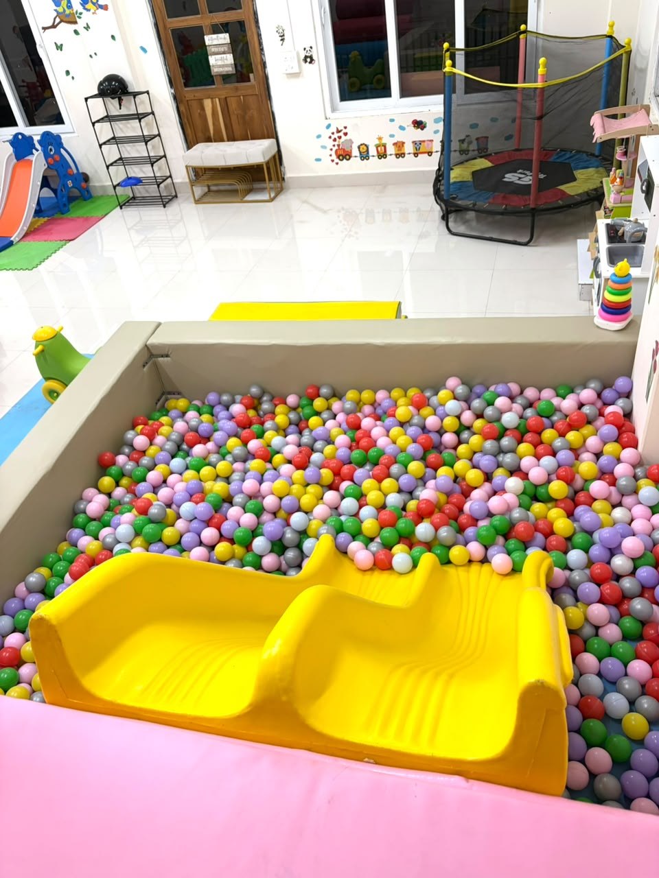 The colourful ball pit and yellow double slide at The Play Hive indoor playground